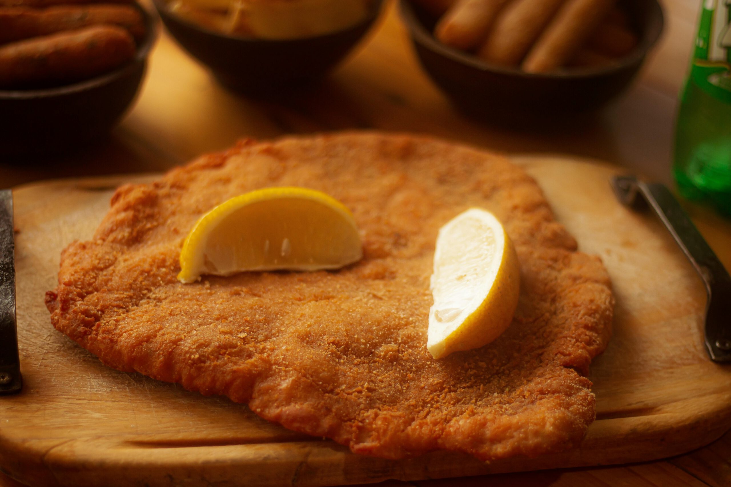 Golden-brown schnitzel topped with lemon wedges on a wooden board, perfect for food photography.